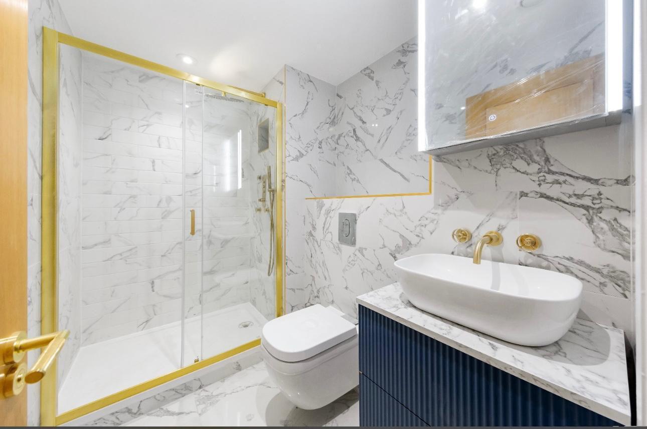 Marble tiled bathroom renovation with brushed brass fixtures, completed by builders in West London